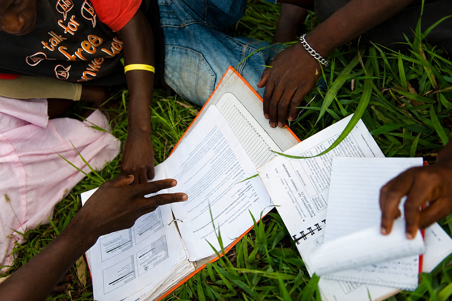 Community members sitting together outdoors reviewing health records and notebooks